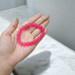 A handcrafted stretchable Pink Onyx bracelet with 8mm light pink beads arranged in a circle on a white background