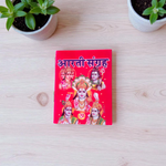 Aarti Sangrah Book in Hindi with traditional cover art, placed beside diya and idol in a temple setting