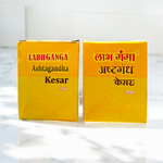Ashtaganda kesar kumkum containers placed with puja items like diya, flowers, and yantra paper