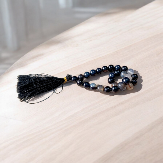 Close-up of Natural Sulemani Hakik Mala with 27+1 round 8mm black agate beads, arranged in a wrist-sized loop on a white background