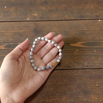 Image of two adjustable spiritual bracelets – one made with white Vaijanti seeds and the other with brown Kamal Gutta beads – displayed on a natural surface