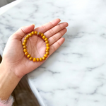 Image of two stretchable bracelets – one made with white Vaijanti seeds and one with yellow Haldi beads – arranged side by side on a natural background