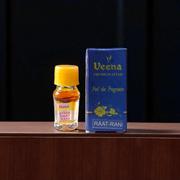 1ML bottle of Raat Rani Attar with applicator placed beside night-blooming jasmine flowers and diya lamp on a wooden altar