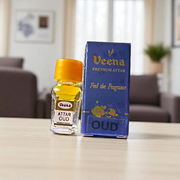 2ML glass bottle of OUD Attar by Veena, featuring a sleek gold cap and minimalist label, placed on a dark wooden surface with pieces of agarwood