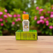 A 2ML bottle of Kewra Attar by Veena placed next to Kewra flowers, highlighting its traditional use in meditation and worship