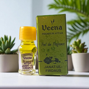 A 2ML roll-on bottle of Janat-UL-Firdaus Attar by Veena, placed alongside aromatic herbs and floral elements, symbolizing purity and spirituality