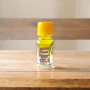 A 2ML roll-on bottle of Janat-UL-Firdaus Attar by Veena, placed alongside aromatic herbs and floral elements, symbolizing purity and spirituality