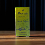 A 2ML roll-on bottle of Janat-UL-Firdaus Attar by Veena, placed alongside aromatic herbs and floral elements, symbolizing purity and spirituality