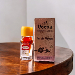 A 2ML roll-on bottle of Veena’s Musk Amber Attar placed elegantly with natural ingredients in the background, showcasing luxury and tradition