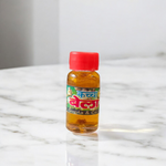 A 4ML roll-on bottle of Bela Attar by Veena, placed with jasmine (Bela) flowers on a wooden surface, symbolizing purity, peace, and tradition
