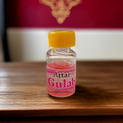 A 4ML roll-on bottle of Gulab Attar by Veena, displayed with rose petals around it, symbolizing purity, romance, and timeless floral elegance