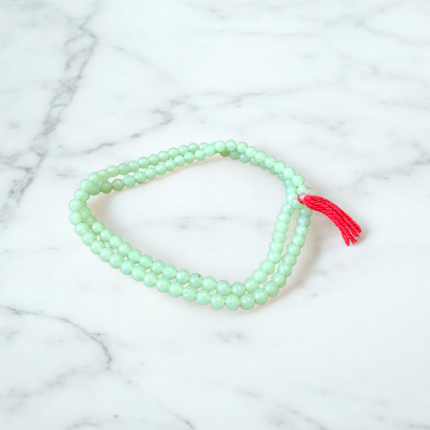 A beautiful 108+1 bead Green Moti Mala made of small, smooth pearl-like green beads strung for japa or spiritual wear