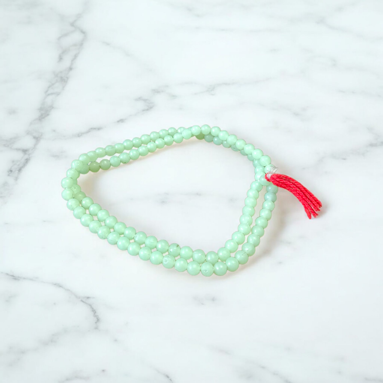A beautiful 108+1 bead Green Moti Mala made of small, smooth pearl-like green beads strung for japa or spiritual wear