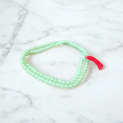 A beautiful 108+1 bead Green Moti Mala made of small, smooth pearl-like green beads strung for japa or spiritual wear