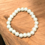 A beautiful 8mm stretchable natural pearl bracelet featuring round, white freshwater pearls on an elastic cord, ideal for healing and style