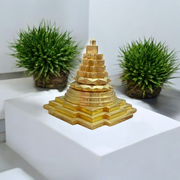 A beautifully crafted brass Meru Shri Yantra placed on a wooden pooja altar, with intricate geometric detailing and divine presence