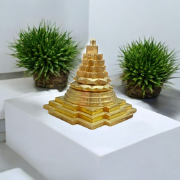 A beautifully crafted brass Meru Shri Yantra placed on a wooden pooja altar, with intricate geometric detailing and divine presence