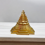A beautifully crafted brass Meru Shri Yantra placed on a wooden pooja altar, with intricate geometric detailing and divine presence