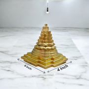 A beautifully crafted brass Meru Shri Yantra placed on a wooden pooja altar, with intricate geometric detailing and divine presence