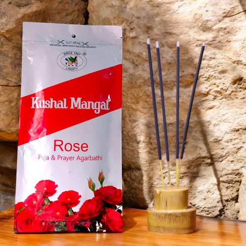 A bundle of hand-rolled Rose Incense Sticks by Kushal Mangal, placed on a holder with light smoke, symbolizing peace and natural fragrance