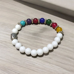 A handcrafted 7 Chakra Bracelet with White Agate and Howlite beads arranged in a circular elastic design, ideal for spiritual healing and meditation