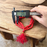 A handcrafted Lal Moonga Mala with 108+1 round red coral beads (6mm), used for puja and meditation, laid out on a spiritual backdrop