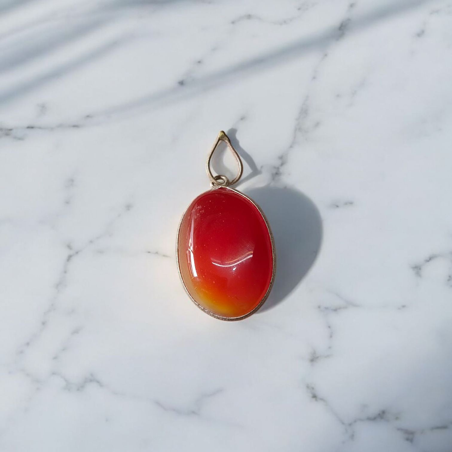 A handcrafted Natural Carnelian and Orange Aventurine pendant in sterling silver setting, displayed on a wooden background