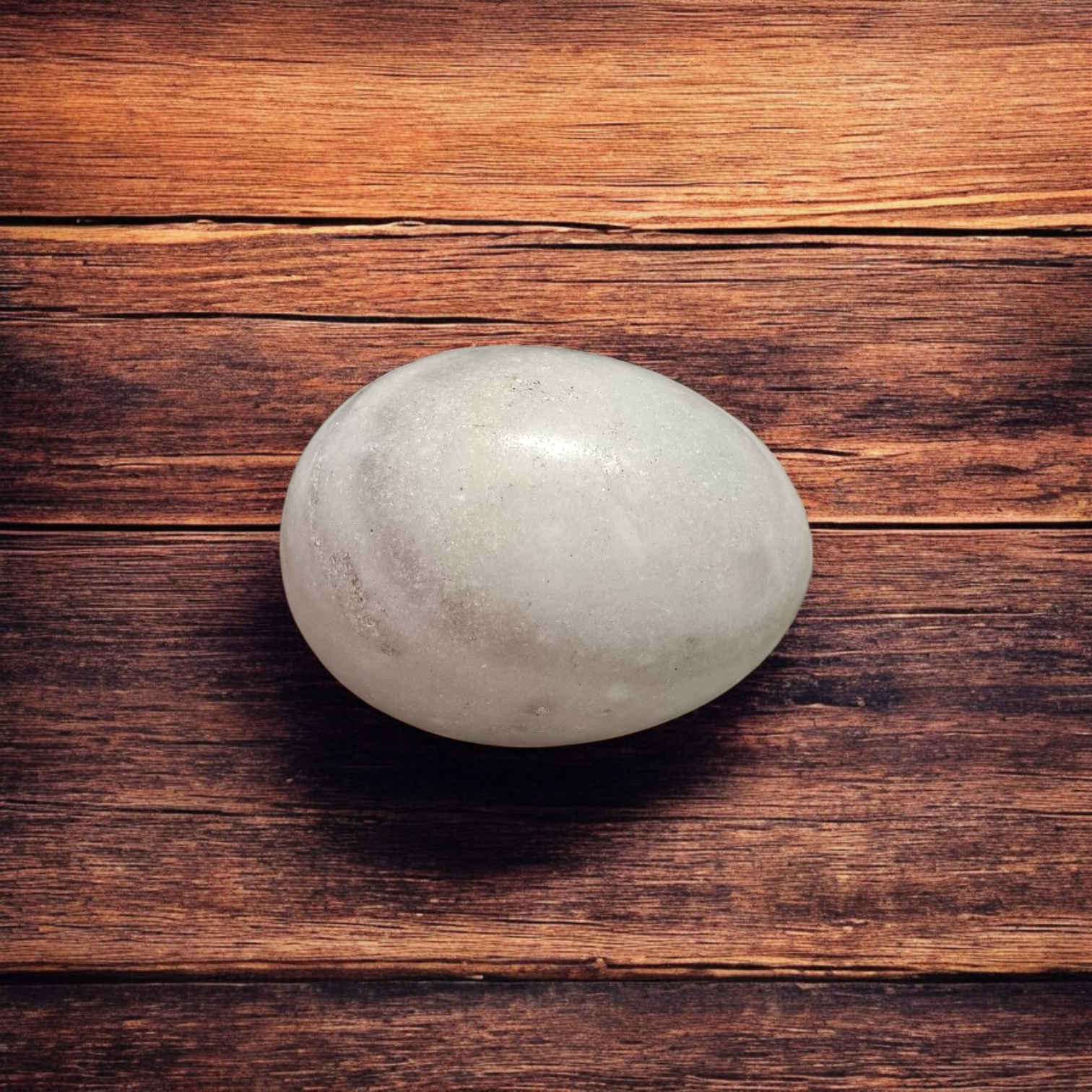 A handcrafted white and black marble Shivling placed on a clean surface, ideal for Tulsi or temple worship