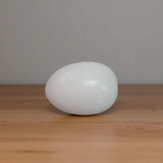 A handcrafted white marble Shivling stone, smooth and polished, ideal for placing under Tulsi plant, home temple, or personal worship altar