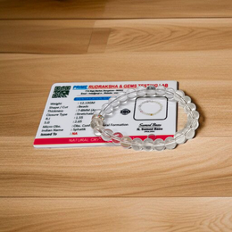 A lab-certified natural Sphatik crystal bracelet with polished 7mm beads, handcrafted and stretchable, resting on a soft white background