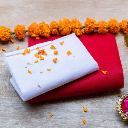 A neatly folded pure white cotton cloth used for Hindu rituals and poojas, displayed on a wooden surface