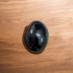 A polished black natural stone Shivling on a smooth base, used for spiritual worship, pooja, and rituals