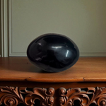A polished black natural stone Shivling on a smooth base, used for spiritual worship, pooja, and rituals