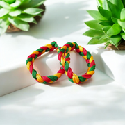 A set of two handmade Resham thread bracelets in vibrant colors, symbolizing good luck, positive energy, and success, displayed on a woman’s wrist