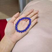 A stretchable Blue Onyx bracelet made of 8mm round beads, arranged neatly in a circular form on a clean white background