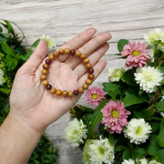 A stretchable bracelet made of alternating white and red 8mm sandalwood beads, displayed on a neutral background