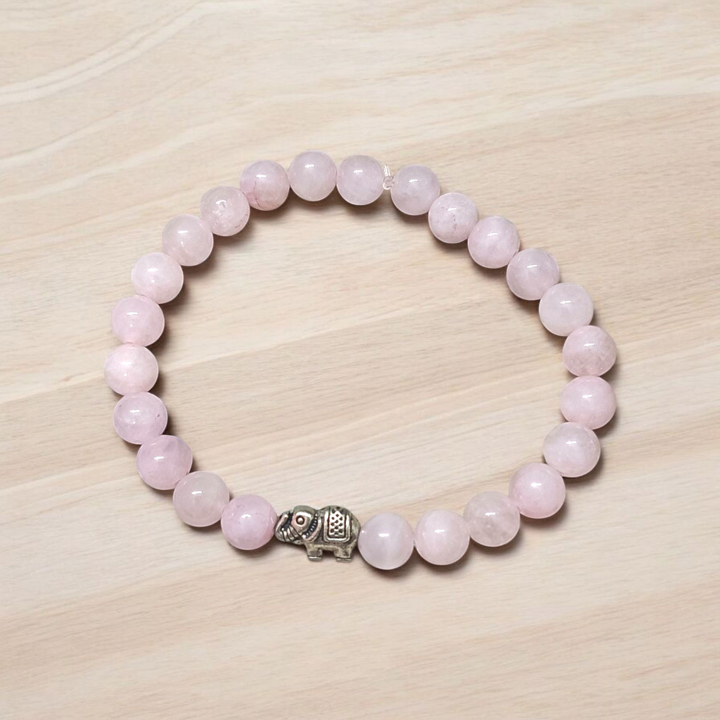 A stretchable natural rose quartz bracelet with 8mm round pink beads, displayed on a white background