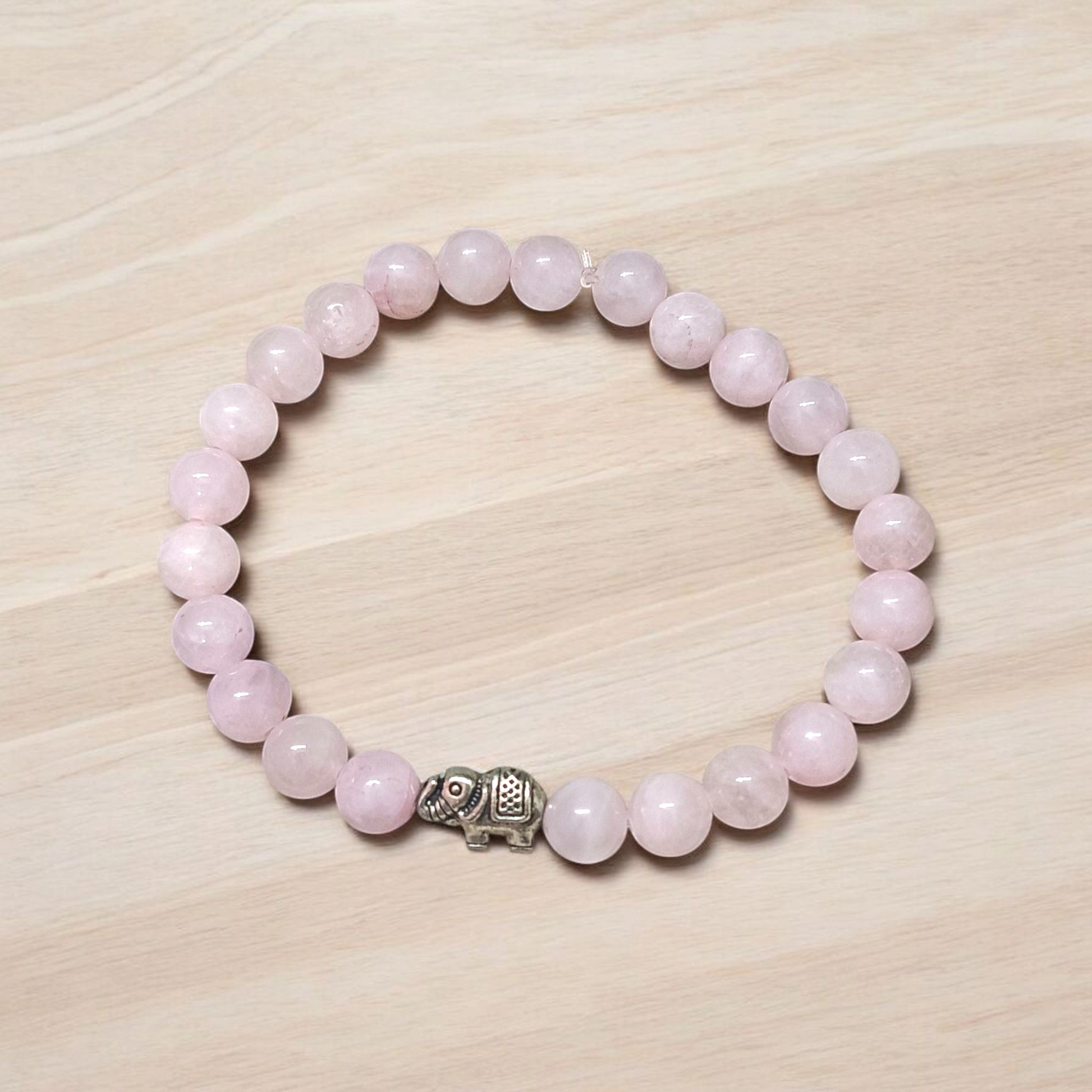 A stretchable natural rose quartz bracelet with 8mm round pink beads, displayed on a white background