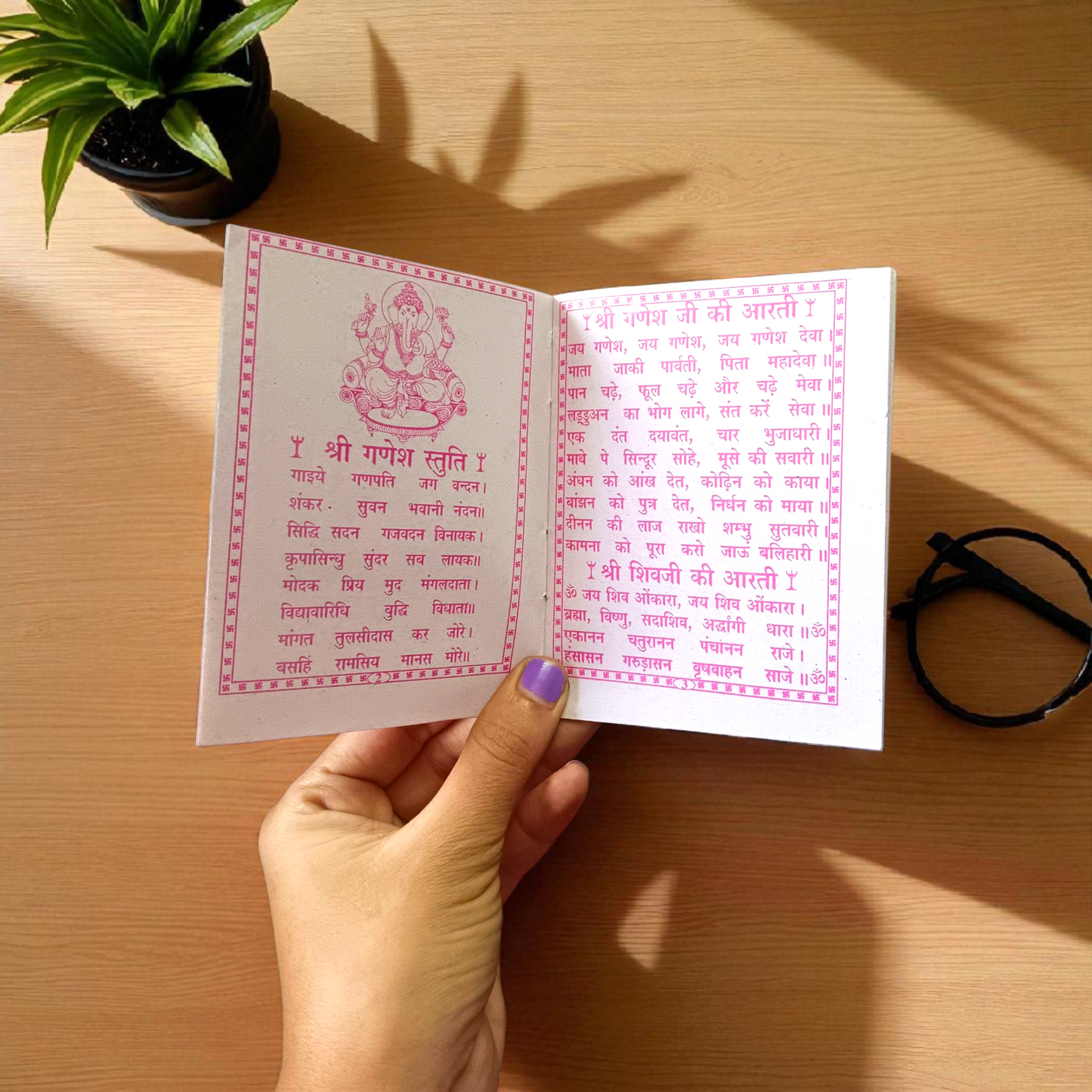 Aarti Sangrah Book in Hindi with traditional cover art, placed beside diya and idol in a temple setting
