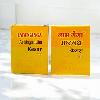 Ashtaganda kesar kumkum containers placed with puja items like diya, flowers, and yantra paper