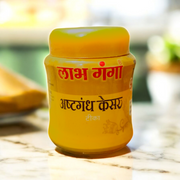 Ashtaganda kesar kumkum containers placed with puja items like diya, flowers, and yantra paper