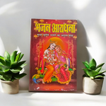 Bhajan Aradhana Hindi Book featuring colorful devotional cover, placed in a traditional worship setup with diya and flowers