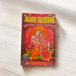 Bhajan Aradhana Hindi Book featuring colorful devotional cover, placed in a traditional worship setup with diya and flowers