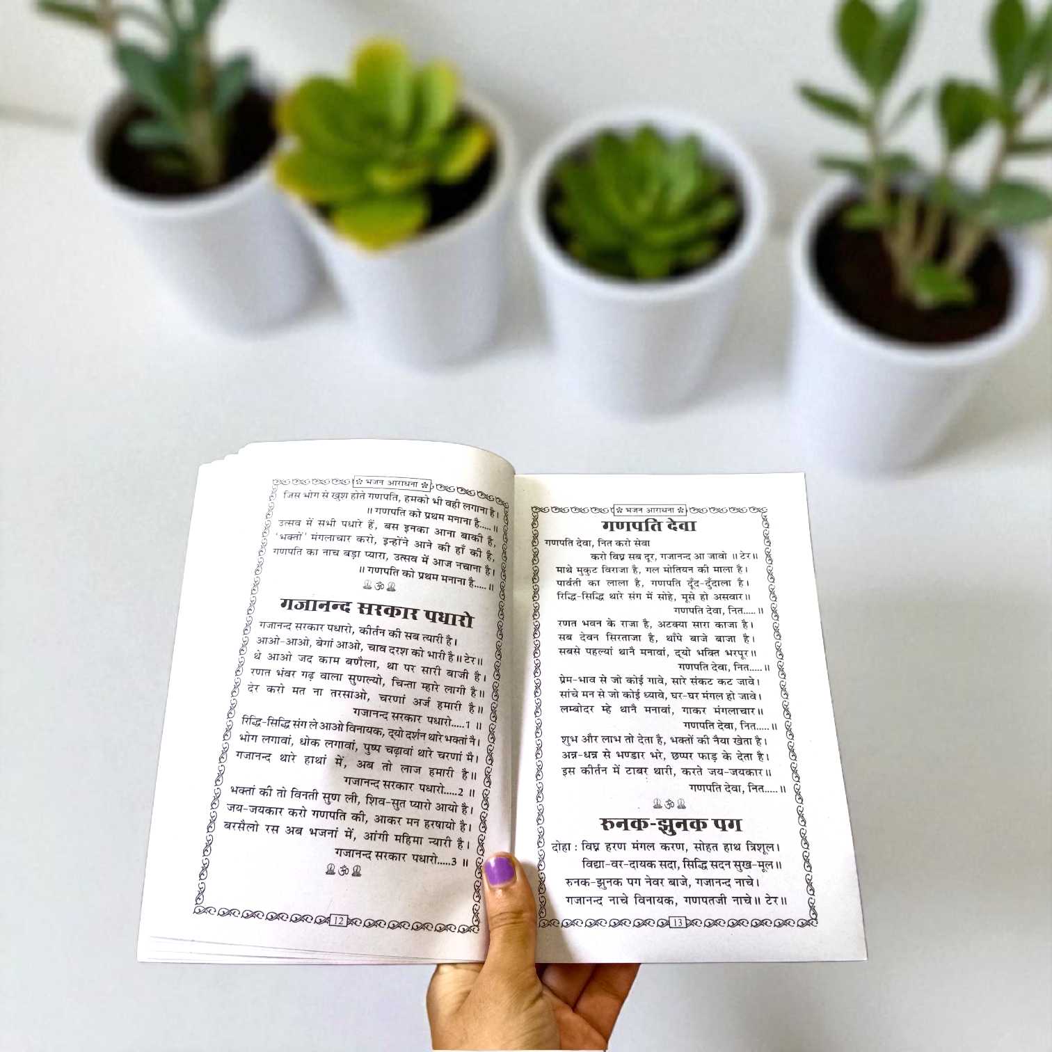 Bhajan Aradhana Hindi Book featuring colorful devotional cover, placed in a traditional worship setup with diya and flowers