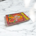 Bhajan Aradhana Hindi Book featuring colorful devotional cover, placed in a traditional worship setup with diya and flowers