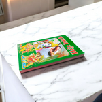 Bhajan Ganga Hindi Book with colorful spiritual design, placed on a wooden prayer stand with diya and flowers