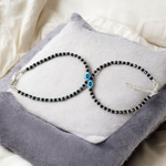 Black bead anklet for women with central evil eye charm, adjustable design for daily wear and spiritual protection by MALAWALA