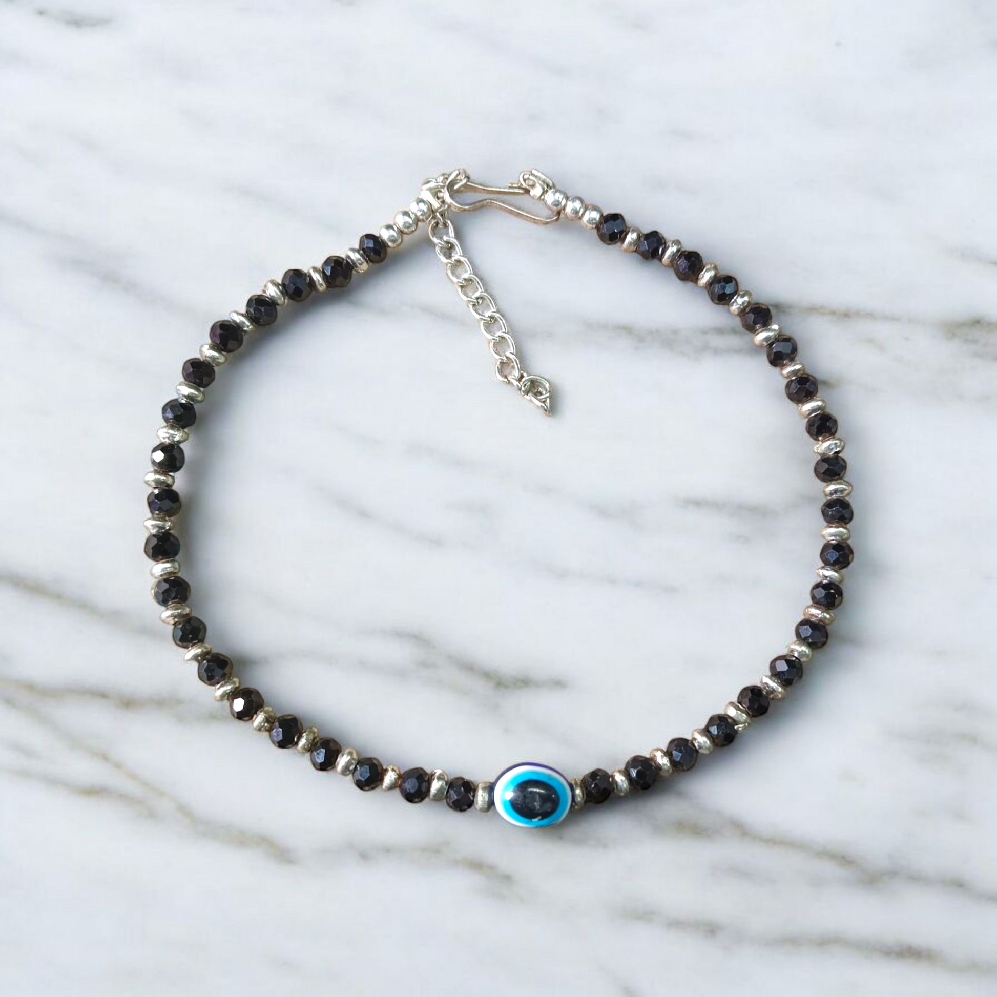 Black bead anklet for women with central evil eye charm, adjustable design for daily wear and spiritual protection by MALAWALA