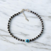 Black bead anklet for women with central evil eye charm, adjustable design for daily wear and spiritual protection by MALAWALA