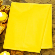 Bright yellow cotton cloth neatly folded and placed on a wooden surface for pooja and religious use